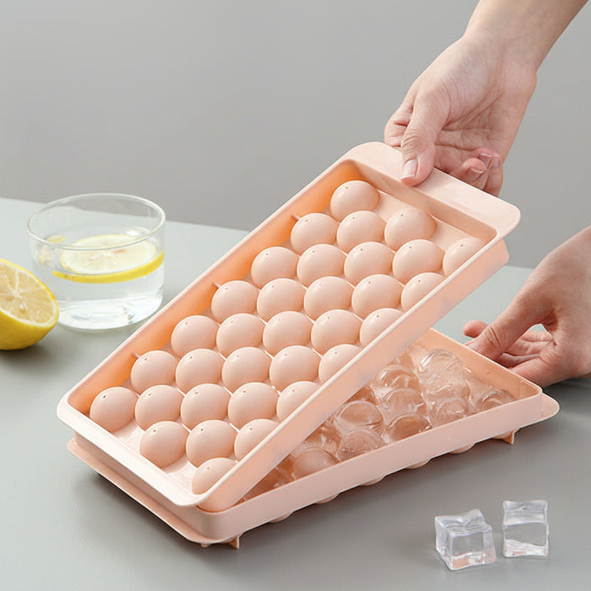 Person holding a pink egg freezing tray with small holes on a gray surface.